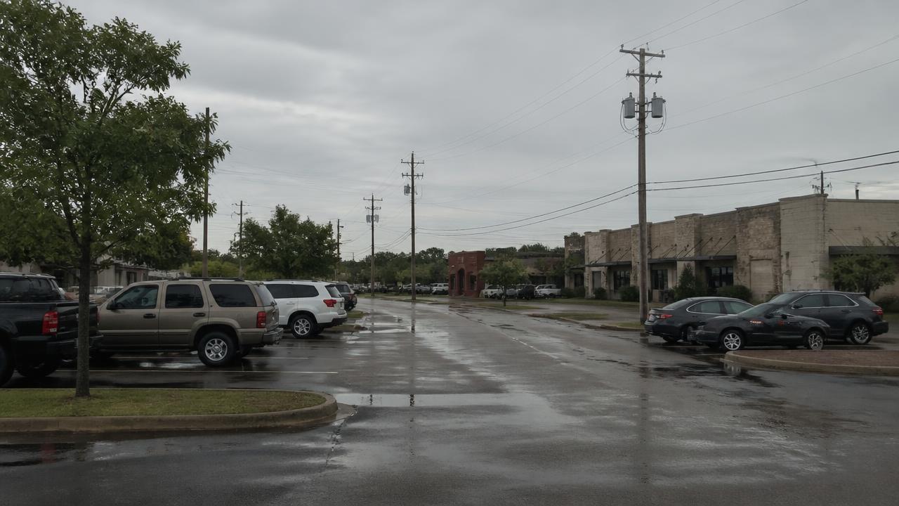 Service business storefronts along a street after rain