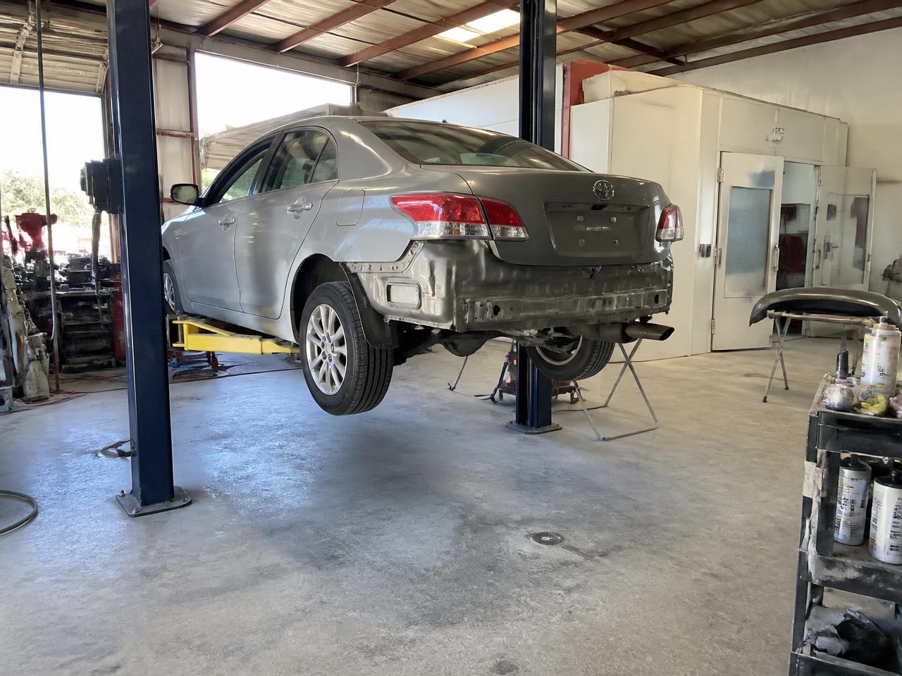 Sedan raised on a lift inside an independent collision repair shop